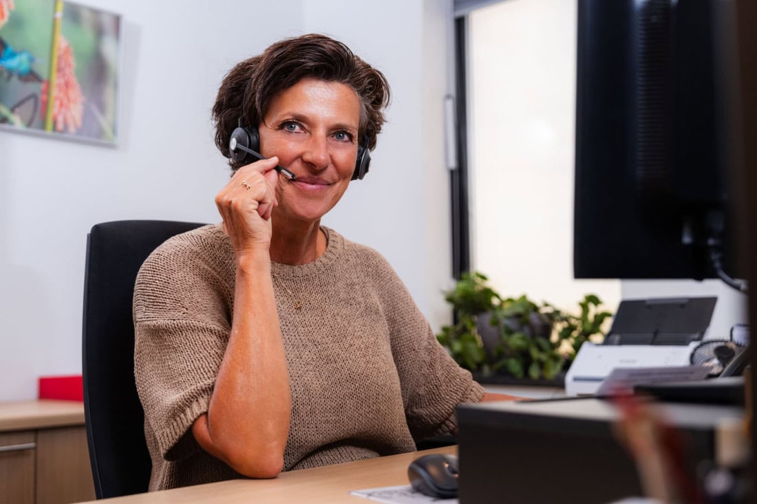 Care assistant with headset helps with GP and GP station queries, customer-oriented service.