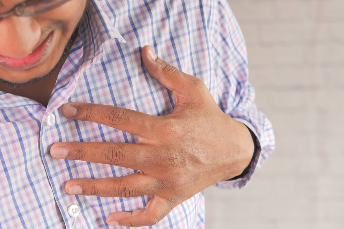 Cardiovascular disease: man holds breast due to pain or discomfort, healthcare and prevention.