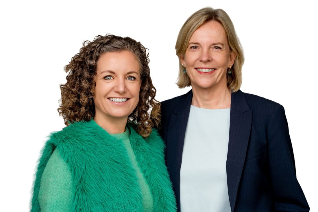 Hoge kwaliteit portret van twee lachende vrouwen in professionele kleding, zakelijke setting.
